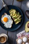Um ovo frito e um pão integral com abacate no café da manhã — Fotografia de Stock