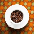Крупный план кофейных зерен в кофейной чашке — стоковое фото