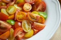 Bunte Tomaten, halbiert und geviertelt, auf einem Teller — Stockfoto