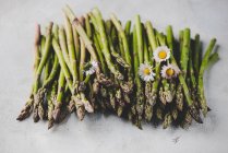 Green asparagus with daisies — Stock Photo