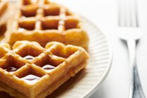Belgian waffle pieces with syrup drpping down side — Stock Photo