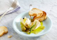 Eingelegter cremiger Camembert mit Oliven, Zwiebeln und Salbei serviert mit gegrilltem Baguette — Stockfoto