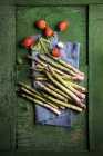 Fragole e asparagi verdi su un panno di lino blu — Foto stock