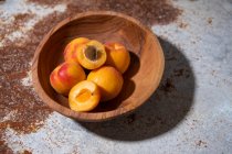 Свежие абрикосы в деревянной чаше на деревенской металлической поверхности — стоковое фото