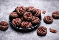 Pecan chocolate biscuits in plate and on stone surface — Stock Photo