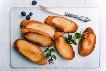 Toasted baguette slices with margarine, mint and blueberries — Stock Photo