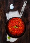 Salsa de tomate con cebolla roja y perejil en una sartén - foto de stock