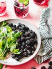 Blackberries and mint leaves on white plate — Stock Photo