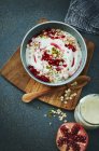 Bowl of pomegranate granola with yoghurt on wooden board — Stock Photo