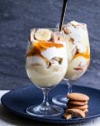 Gläser mit Bananenpudding, geschnittenen Bananen, Waffelkeksen, Vanillepudding, Schlagsahne und Karamellsoße — Stockfoto