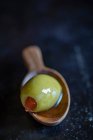 Une olive verte sur une cuillère en bois — Photo de stock
