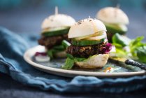 Mini burgers végétaliens avec beignets de lentilles de béluga, laitue d'agneau, radicchio, concombre, oignons et sauce chili — Photo de stock