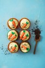 Karotten dekorierte Cupcakes mit orangefarbener Frischkäseglasur und zerkleinerten Keksen — Stockfoto