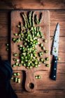 Asparagi verdi tagliati a fette con un coltello su una superficie di legno — Foto stock