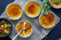 Mehrere Creme Brulee Desserts und Fruchtkompott in Schalen — Stockfoto