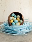 Grande uovo di Pasqua al cioccolato, seduto in un nido di caramelle ai mirtilli, pieno di mini uova di cioccolato — Foto stock