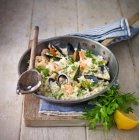 Морепродукты Ризотто, с креветками, мидиями, моллюсками, кальмарами, подается с лимоном и петрушкой — стоковое фото