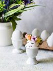 Œufs de Pâques avec des décorations de fleurs dans des tasses à œufs — Photo de stock
