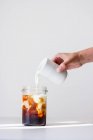 Iced coffee: milk being added to a glass of cold coffee — Stock Photo
