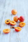 Abricots frais, entiers et coupés en deux sur la surface en bois — Photo de stock
