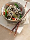 Deep fried tofu coated in black and white sesame seeds rice noodles stir fried vegetables carrots scallions sugar snaps — Stock Photo