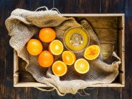 Schachtel mit frischen Orangen - einige gepresst, um frischen Orangensaft herzustellen — Stockfoto