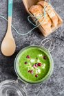 Green cabbage soup in a glass jar with pomegranate seeds and feta cubes — Stock Photo