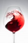 Red wine creating a wave in a glass — Stock Photo