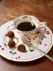 Uma xícara de café e pralinés de chocolate — Fotografia de Stock