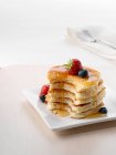 A pile of American pancakes with fruit and honey — Stock Photo