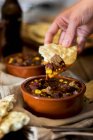 A hand dipping flatbread in a bowl of chilli con carne — Stock Photo