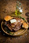 A steak with garlic and butter on a wooden board — Stock Photo