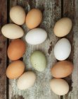 Свіжі яйця різного кольору на дерев'яному фоні — стокове фото