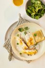 Raviolis rellenos de champiñones cubiertos con parmesano derretido, servidos con lechuga de cordero - foto de stock