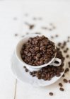 Chicchi di caffè in una tazza di caffè e su un piattino — Foto stock