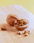 Two walnuts, whole and halved, on a wooden table — Stock Photo