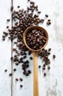 Coffee beans scattered on a table and in a wooden ladle — Stock Photo