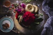 Wedding cake decorated with fresh flowers and gold donuts on table setting with salted caramel sauce — Stock Photo