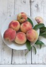 Fresh peaches with leaves on a plate — Stock Photo