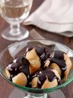 A dish of profiteroles with rich dark chocolate sauce editorial food — Stock Photo