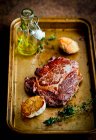 A steak with garlic on a roasting tray — Stock Photo
