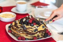 Ein Pfannkuchenkuchen mit Beeren und Schokoladensauce in Scheiben geschnitten — Stockfoto