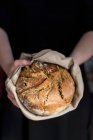 Hands holding clay pot baked beer bread — Stock Photo
