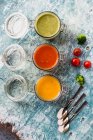 Различные разноцветные супы в стеклянных банках, суп из брокколи, томатный суп, тыквенный суп — стоковое фото