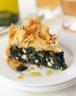 A slice of spinach filo pastry pie on a plate in a table setting — Stock Photo