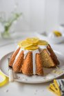 Lemon sponge cake with lemon icing and fresh lemon slices, slice removed — Stock Photo