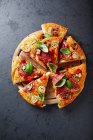 Pizza con champiñones, salami y puerro en una tabla de cortar - foto de stock