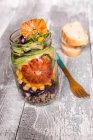 Салат из киноа в стеклянной банке с красной капустой, горохом, авокадо, апельсином и крессом — стоковое фото
