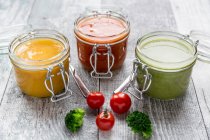 Various colorful soups in glass jars, broccoli soup, tomato soup, pumpkin soup — Stock Photo