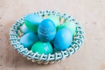 Huevos de Pascua teñidos con patrones batik en una cesta - foto de stock
